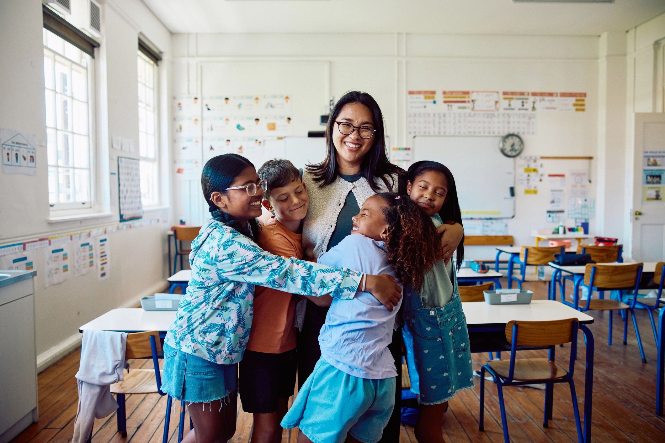 Teacher smiling with children gathered together in a bright classroom